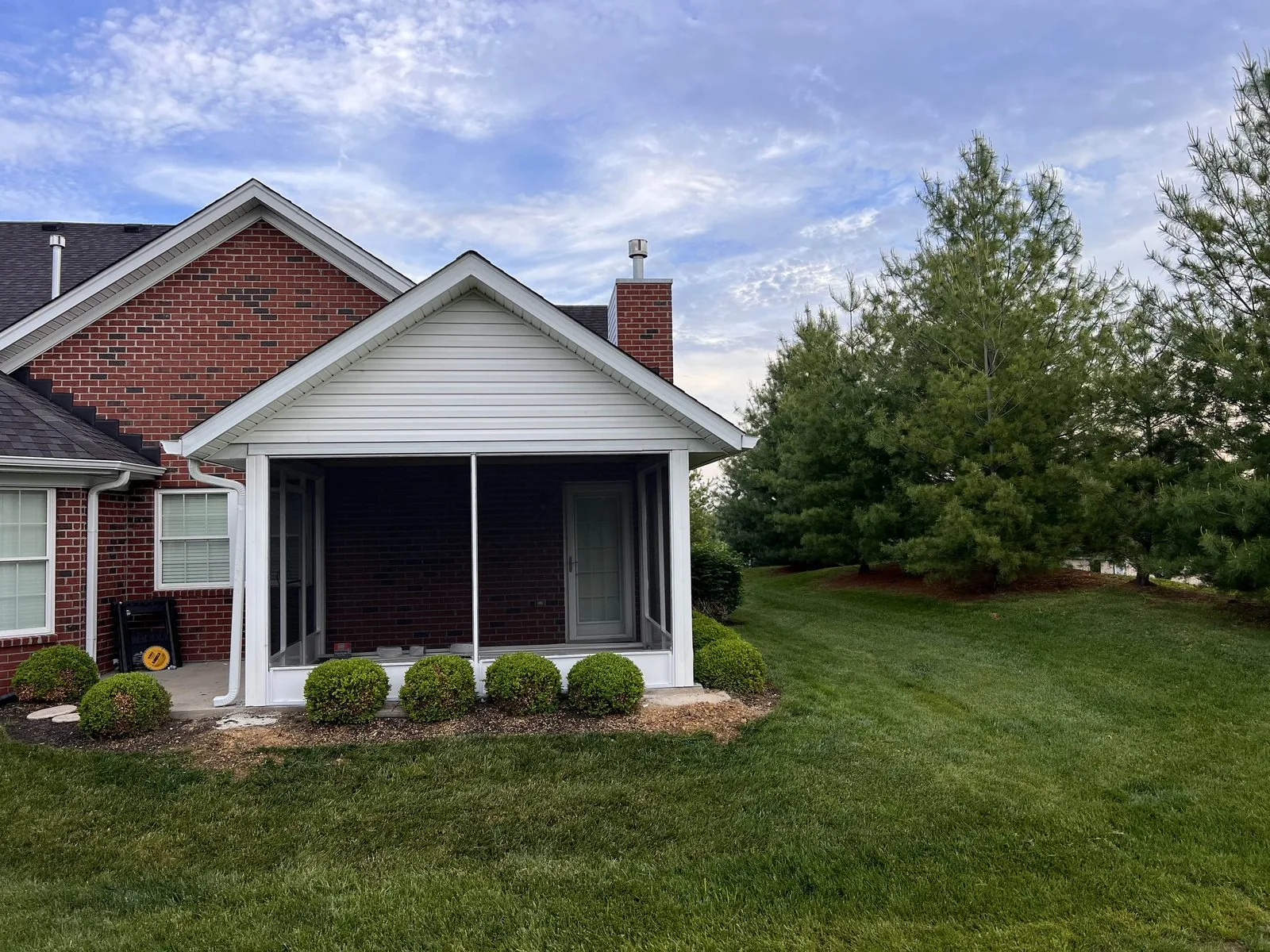 A screened porch addition on a brick home, framed to tie into the existing roofline.