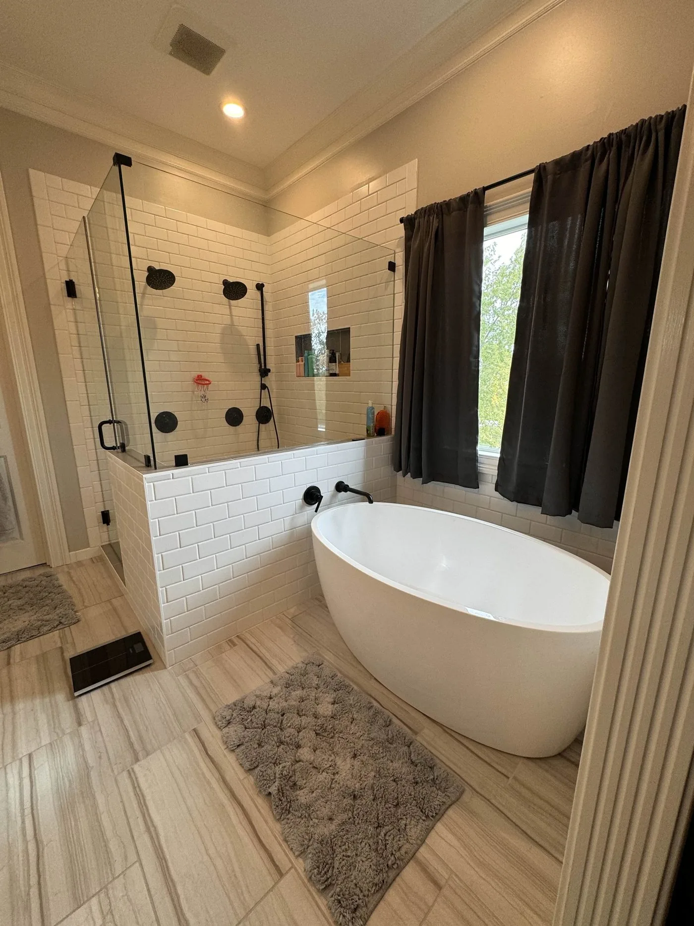 A remodeled bathroom with a freestanding soaking tub, tile flooring and a glass shower.