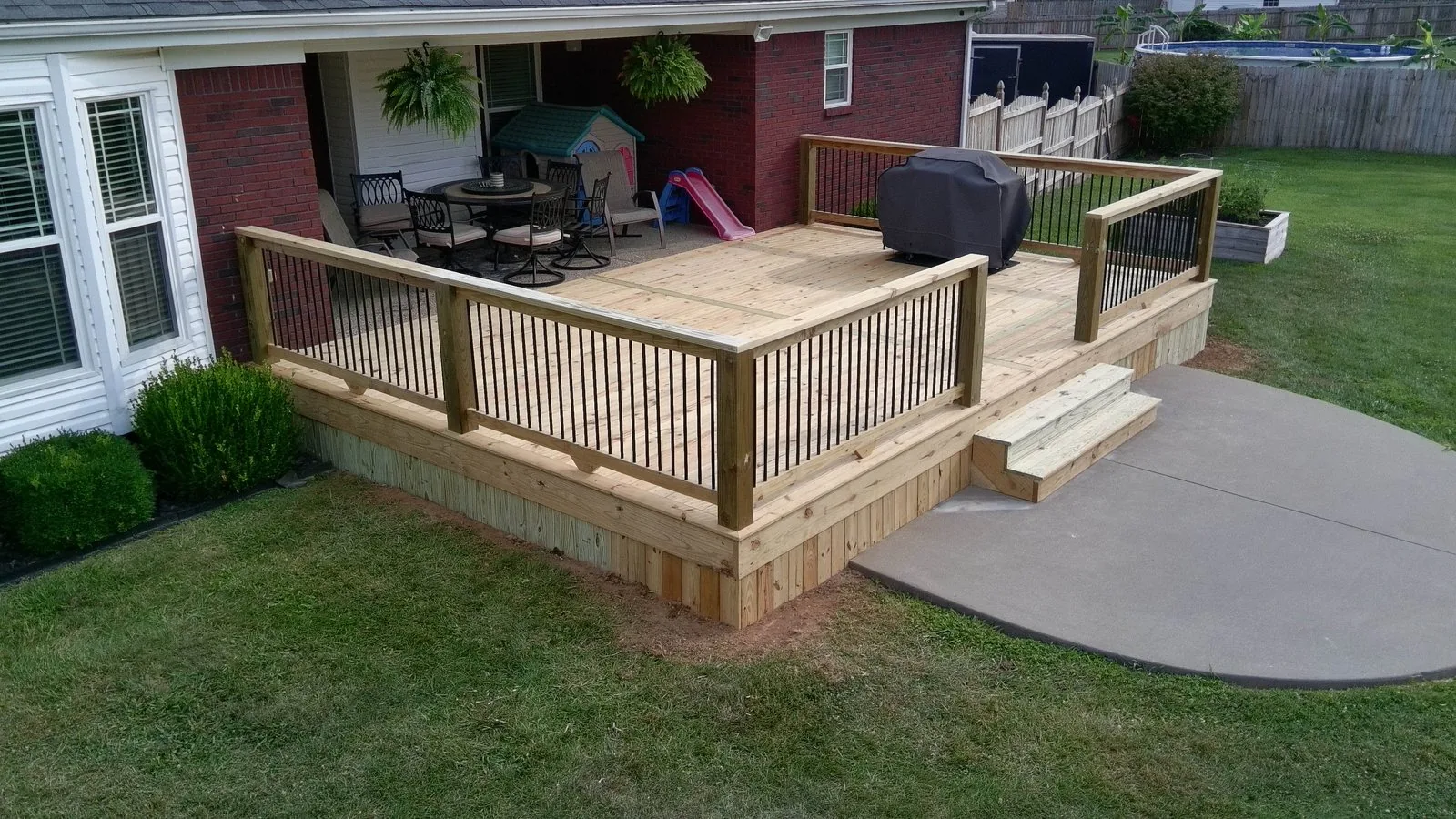 A finished pressure treated deck with black balusters behind a Louisville home.
